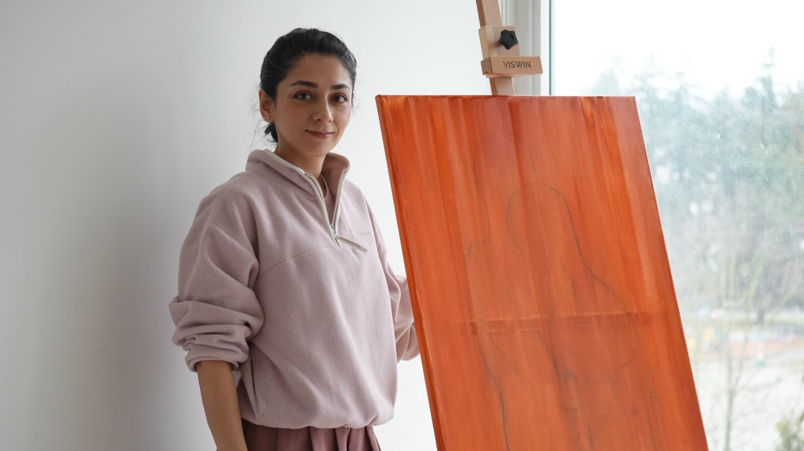 Mahsa in her studio next to a canvas on the easel
