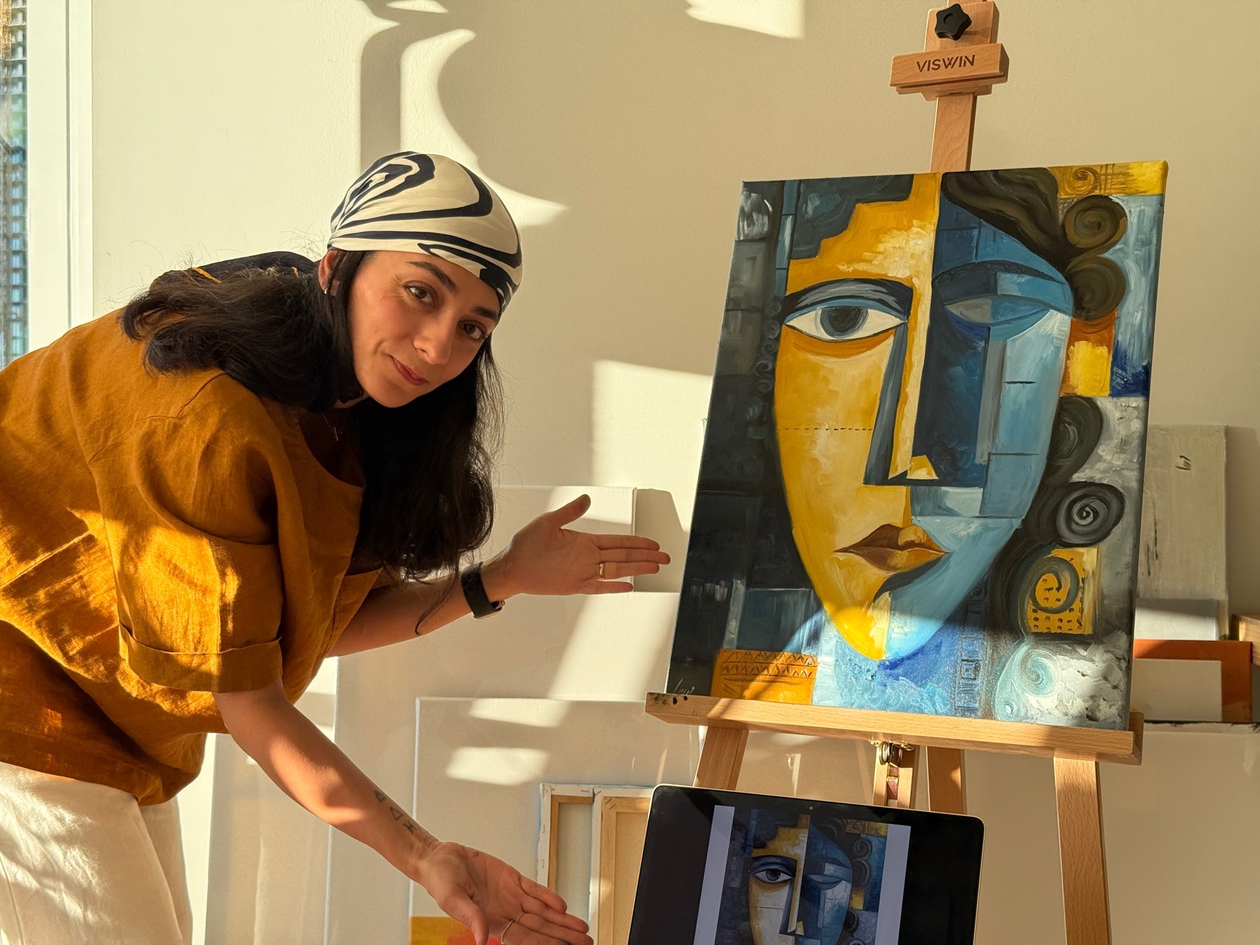 Mahsa in her studio, showing her painting on the easel